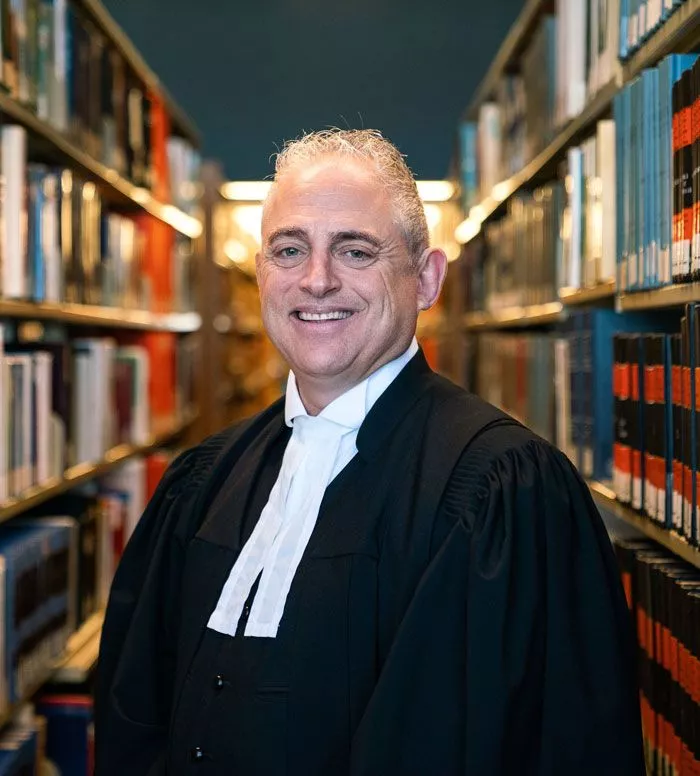 M. Steven Slimovitch, avocat criminaliste qui pose avec un sourire et porte une robe noire d'avocat criminel.